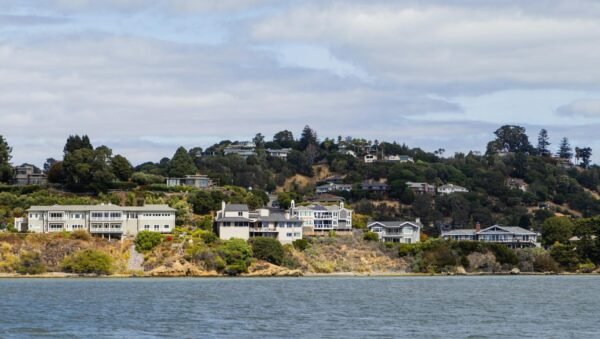 Picturesque view of coastal hillside houses surrounded by lush greenery and waterfront.